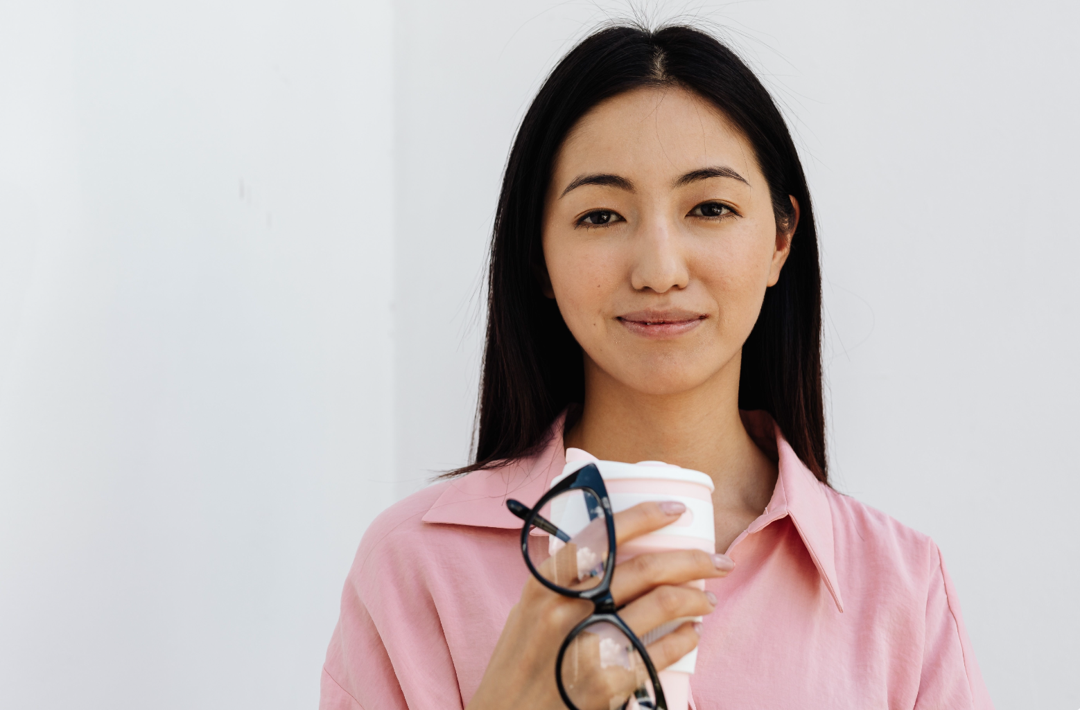 Junge Sachbearbeiterin Treuhand in pinker Bluse mit Kaffeebecher und Brille – Einstieg im Treuhandwesen in der Ostschweiz.
